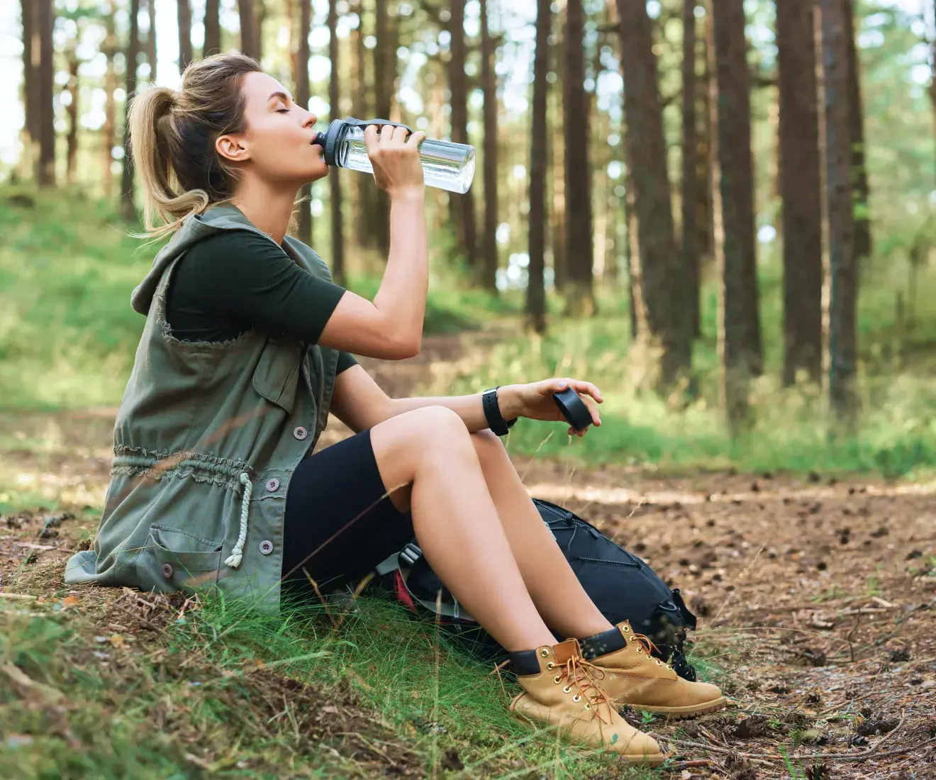 Woman enjoying a glass of water in the woods