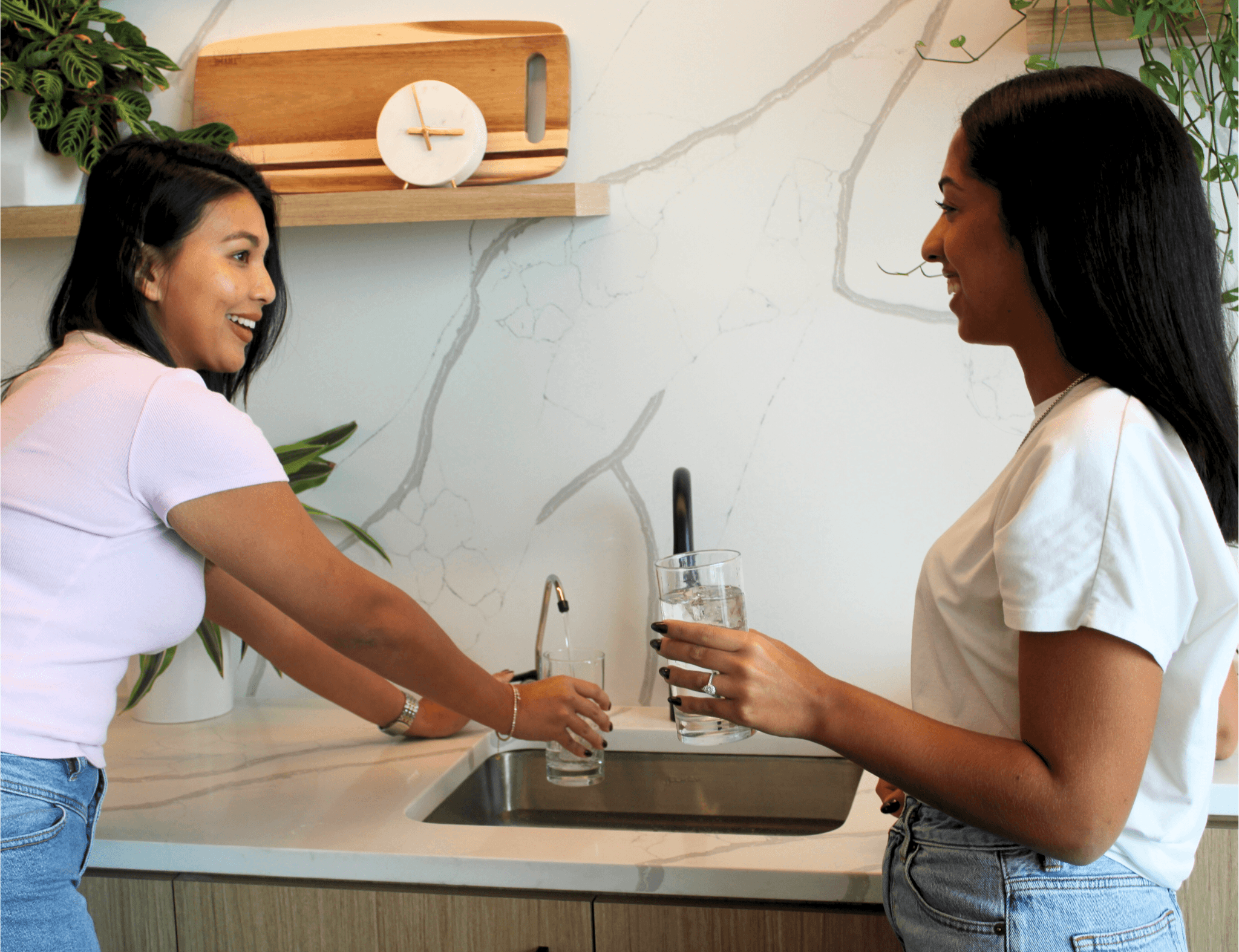 Two women drinking from a sink filtration unit