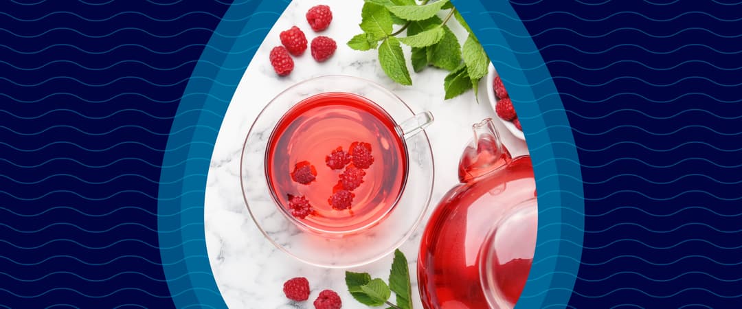 Glass teacup and teapot with raspberry tea, fresh raspberries, and mint leaves on a marble surface, framed by a droplet shape on a wavy blue background.