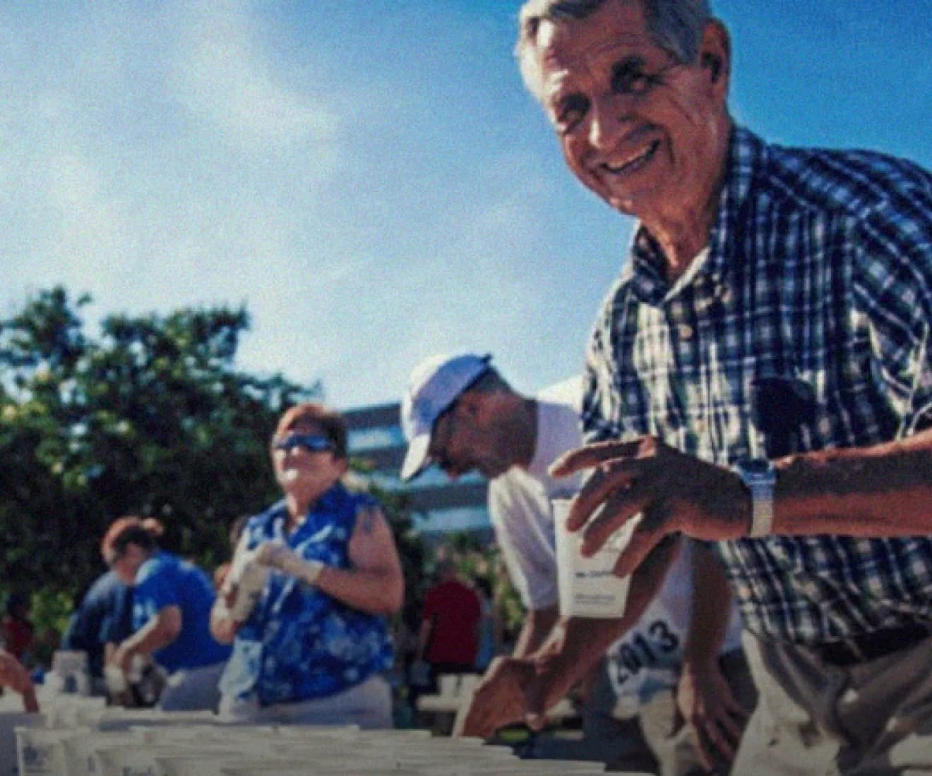 Senior man smiling handing out a cup of water