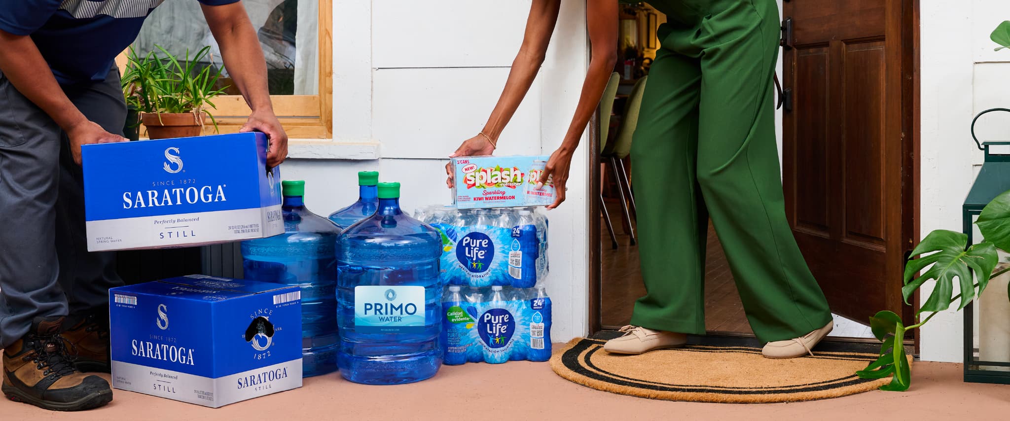 Two people are placing bottled water and large water jugs on a doorstep. Various brands are visible, including Saratoga and Primo.
