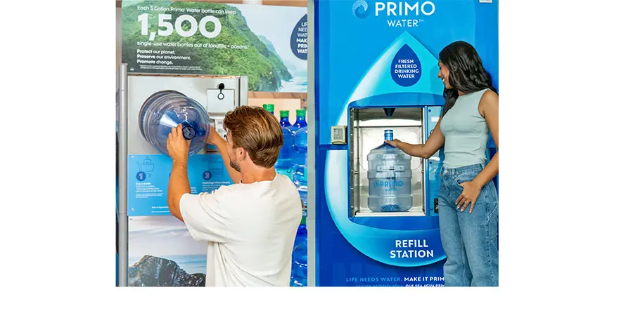 A man refills a large Primo water jug at a refill station, while a woman stands next to a Primo Water vending machine.