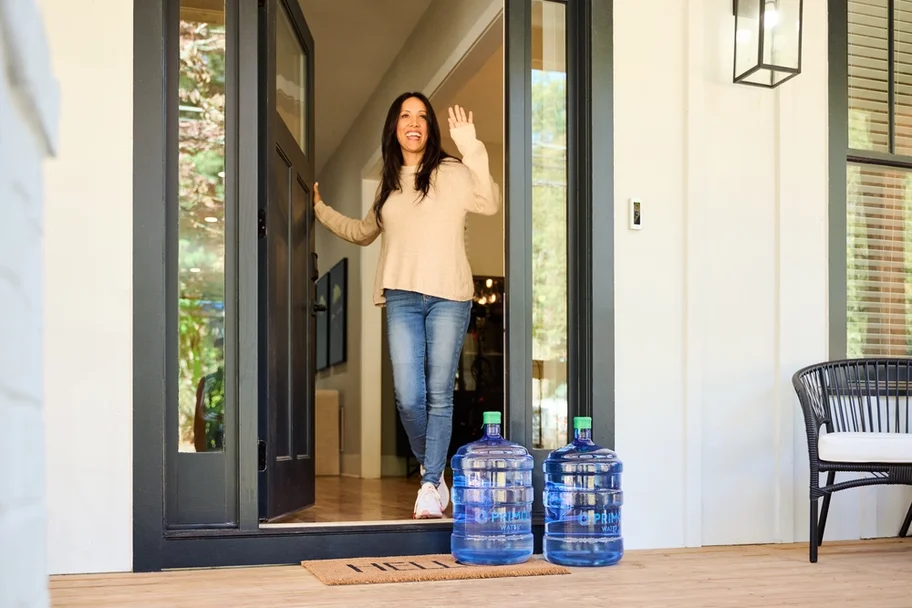 A smiling woman answers the door for her Primo Water home delivery to the front porch